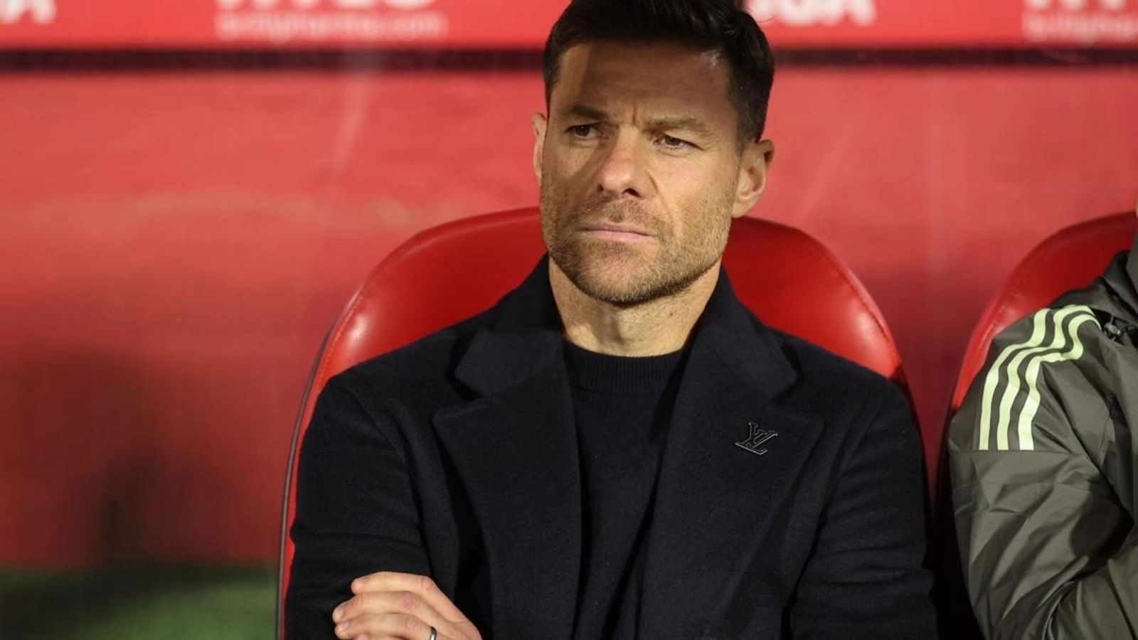 The former player and now Spanish coach sitting on a stadium bench while watching his team play.