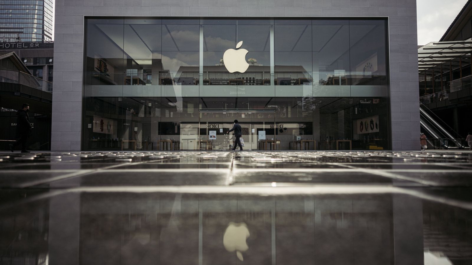 One of Apple’s stores on a rainy day, with its iconic apple logo standing out among other shops
