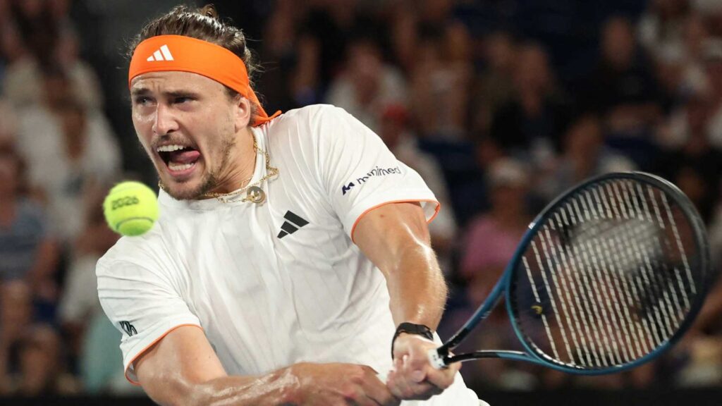 The renowned tennis player about to hit the ball while sticking his tongue out