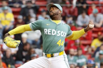 The Cuban pitcher throwing during a game while wearing the Boston team's green uniform