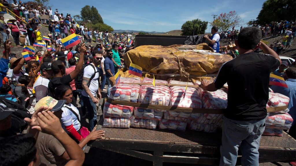A person standing on a truck, coordinating the delivery of humanitarian aid to the Venezuelan people