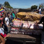 A person standing on a truck, coordinating the delivery of humanitarian aid to the Venezuelan people