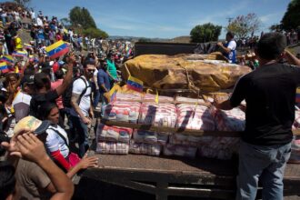 A person standing on a truck, coordinating the delivery of humanitarian aid to the Venezuelan people