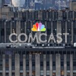 Comcast splits Its empire: NBCUniversal to begin a new independent chapter The COMCAST company name displayed at the top of a tall building in its distinctive multicolored branding