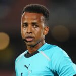 The African referee in the middle of a match wearing a blue uniform