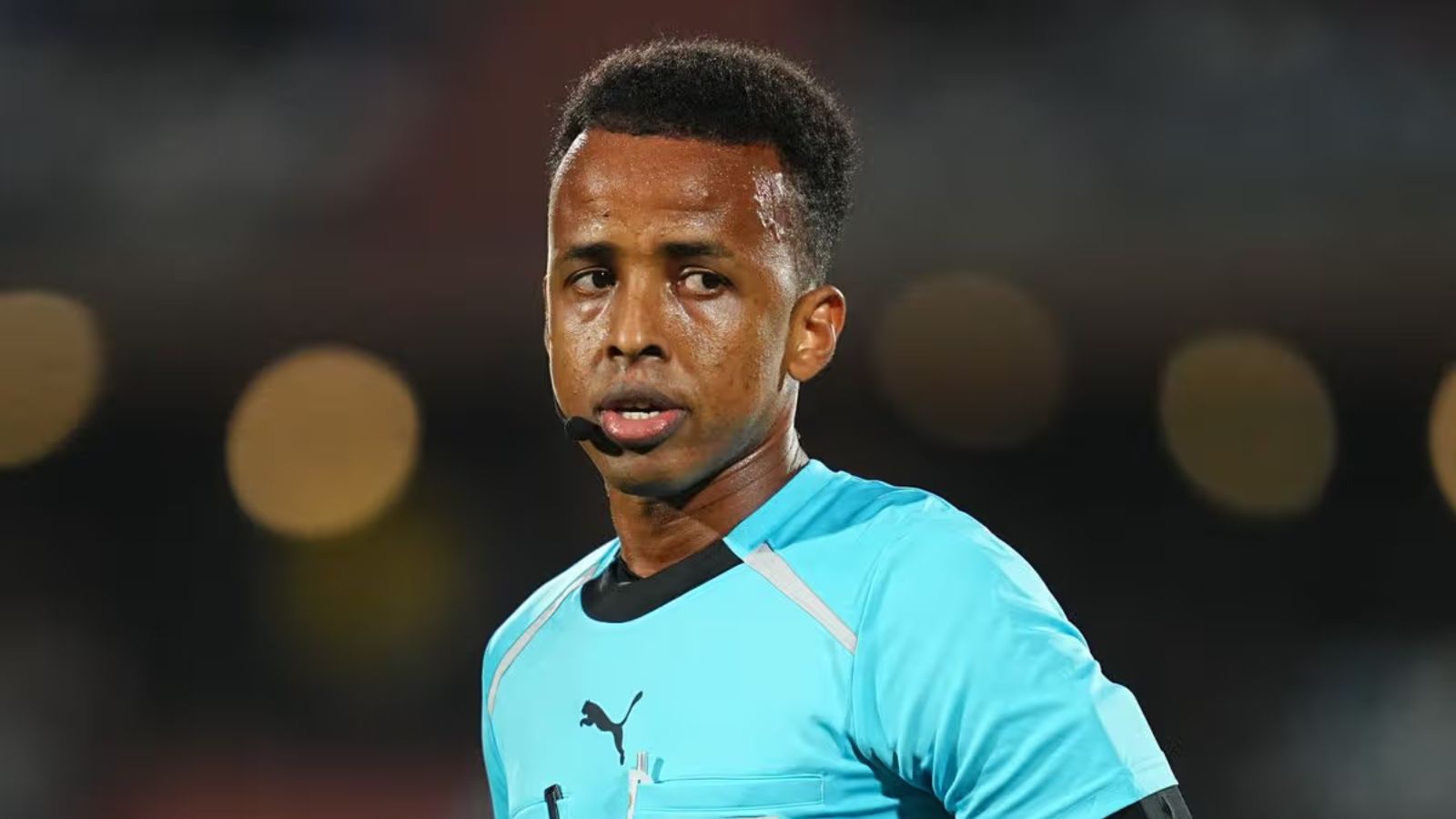 The African referee in the middle of a match wearing a blue uniform