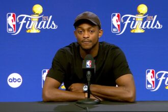 Fox sitting at a table after the game, speaking during a press conference