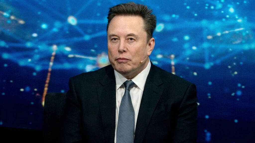 Elon Musk wearing a sharp suit while speaking at a press conference