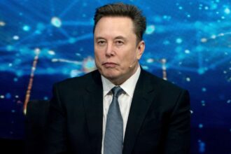 Elon Musk wearing a sharp suit while speaking at a press conference
