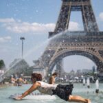 Several people swimming in a pool in front of the Eiffel Tower due to the extreme heat