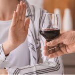 A person pushing away a glass of alcohol with their hands