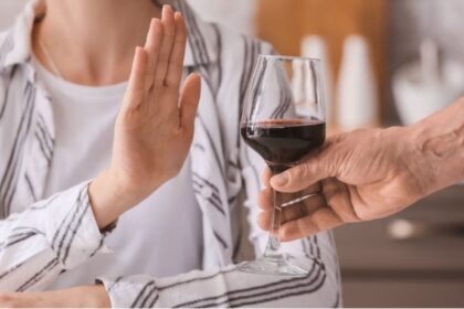 A person pushing away a glass of alcohol with their hands