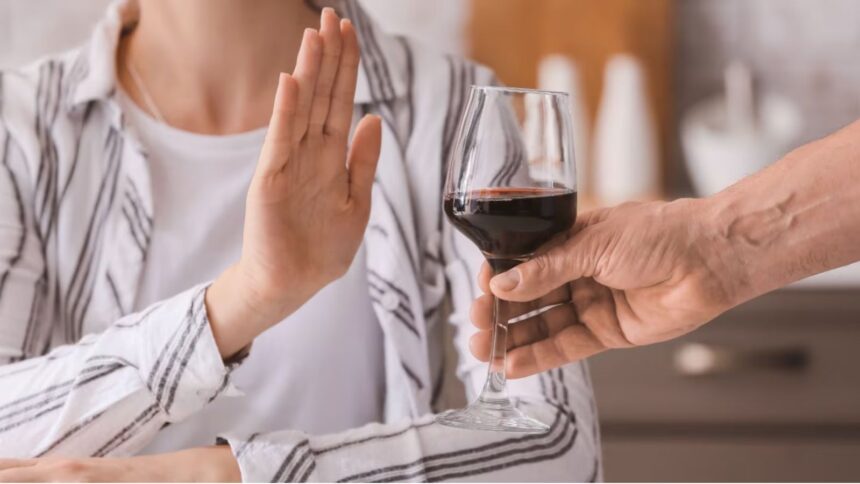 A person pushing away a glass of alcohol with their hands