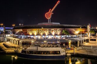 A panoramic view of the Hard Rock Cafe at night, with its eye-catching lights illuminated