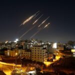 Several missiles being launched from their launchers toward a city