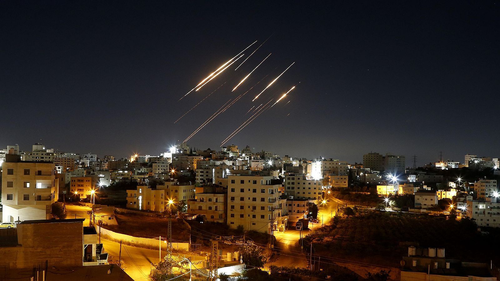 Several missiles being launched from their launchers toward a city