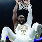 The American player making an incredible dunk while wearing his white and gold uniform