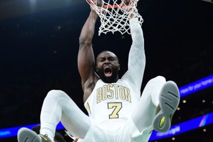 The American player making an incredible dunk while wearing his white and gold uniform