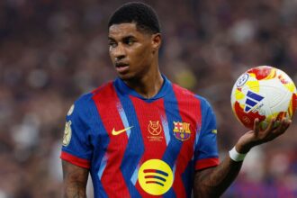 The English player holding the ball in one hand while looking toward the fans in the stadium