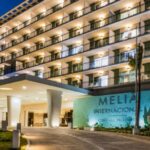 A panoramic photo of the hotel entrance with its logo and name displayed outside the building