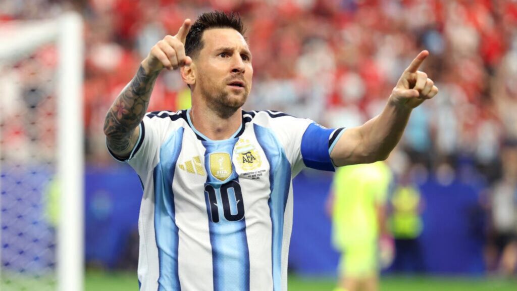 Messi celebrating his goal while pointing toward his family in the stadium stands