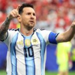 Messi celebrating his goal while pointing toward his family in the stadium stands