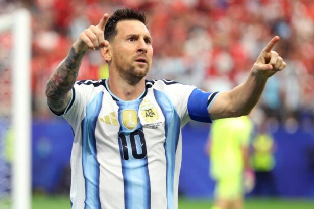 Messi celebrating his goal while pointing toward his family in the stadium stands