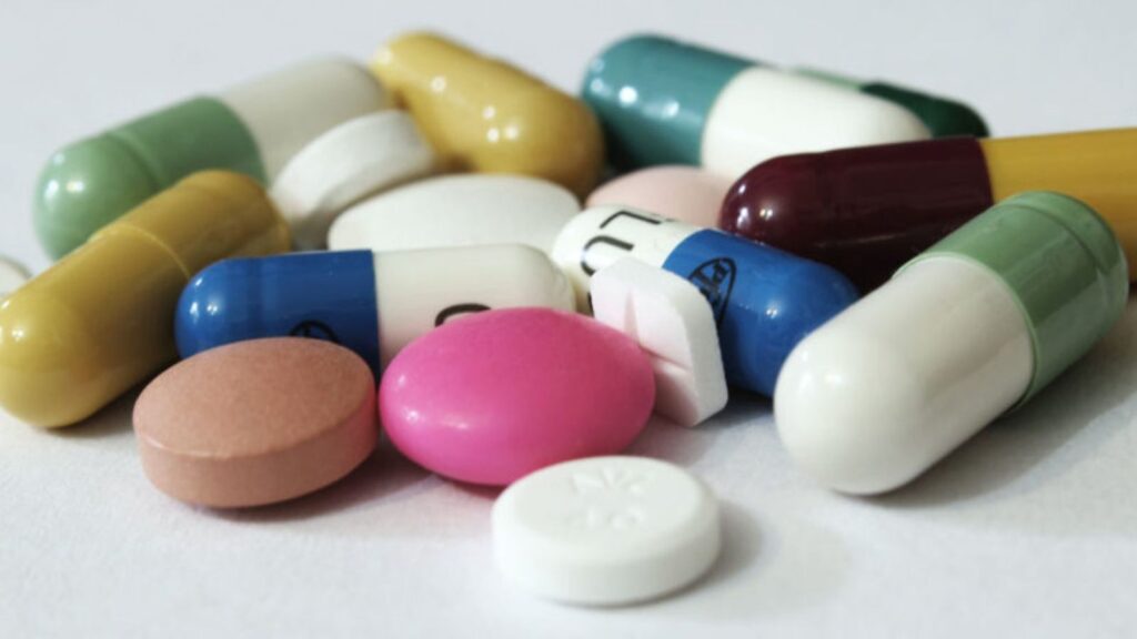 A white background with several pills scattered around, some stacked on top of each other
