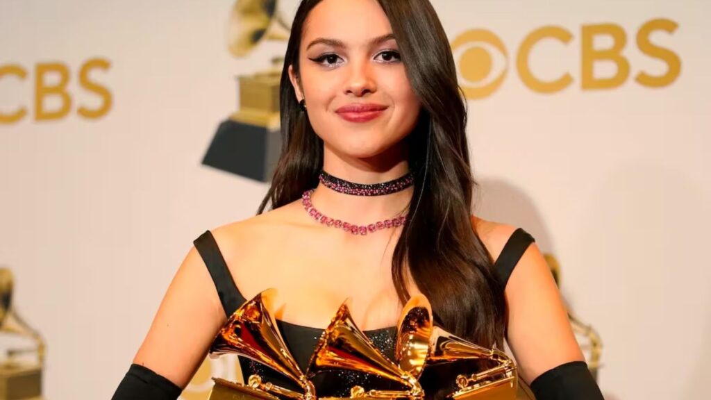 The well-known singer holding three Grammy awards in her arms on a red carpet