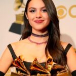 The well-known singer holding three Grammy awards in her arms on a red carpet