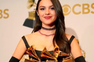 The well-known singer holding three Grammy awards in her arms on a red carpet