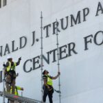 Workers removing Trump's name from a large wall