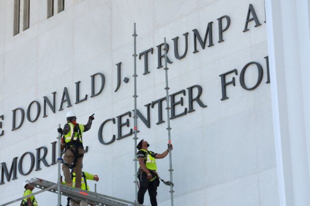 Workers removing Trump's name from a large wall