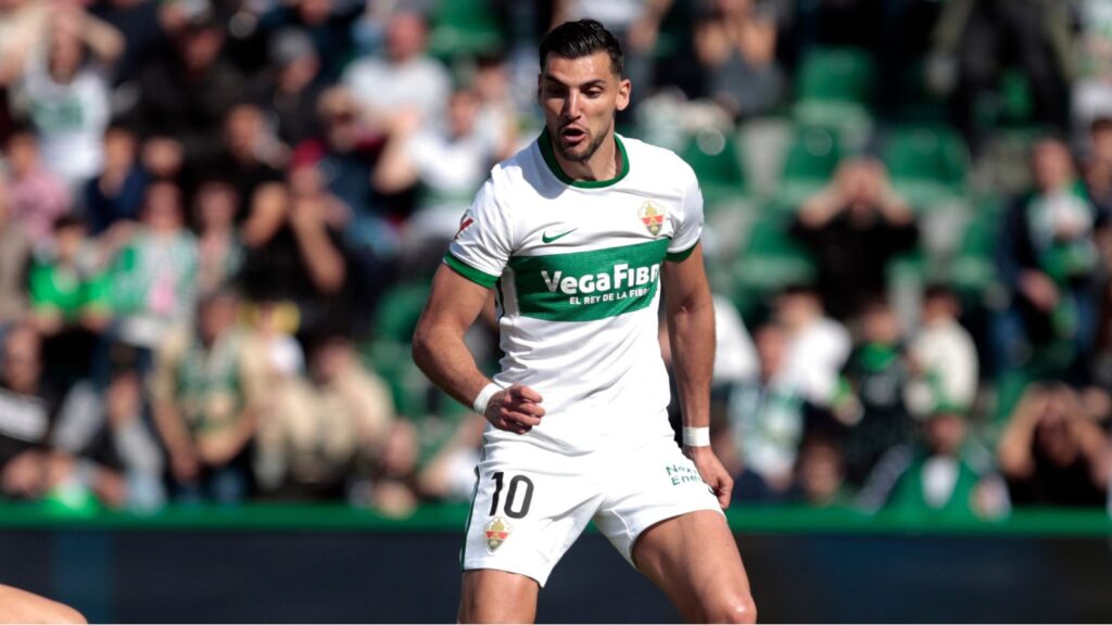 The well-known Elche player running during a match while wearing his white and green uniform