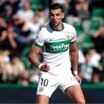 The well-known Elche player running during a match while wearing his white and green uniform