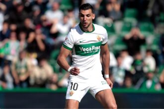 The well-known Elche player running during a match while wearing his white and green uniform