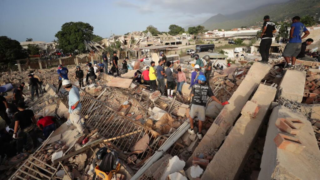 Several rescue workers standing on top of the rubble of a collapsed building while searching for survivors