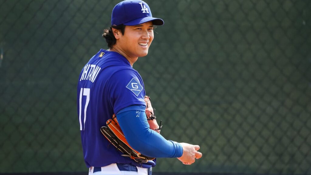 The Japanese star holding the baseball and his glove while smiling at one of his teammates