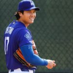 The Japanese star holding the baseball and his glove while smiling at one of his teammates