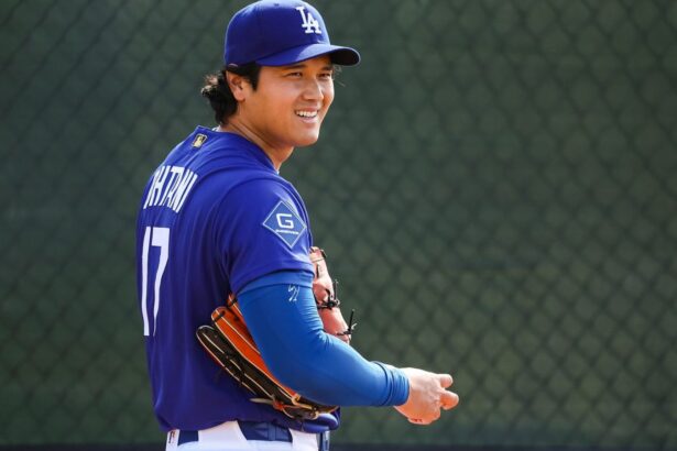The Japanese star holding the baseball and his glove while smiling at one of his teammates