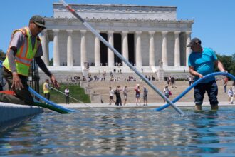 Several people with drainage equipment removing water from the important and well-known park in Washington D.C.