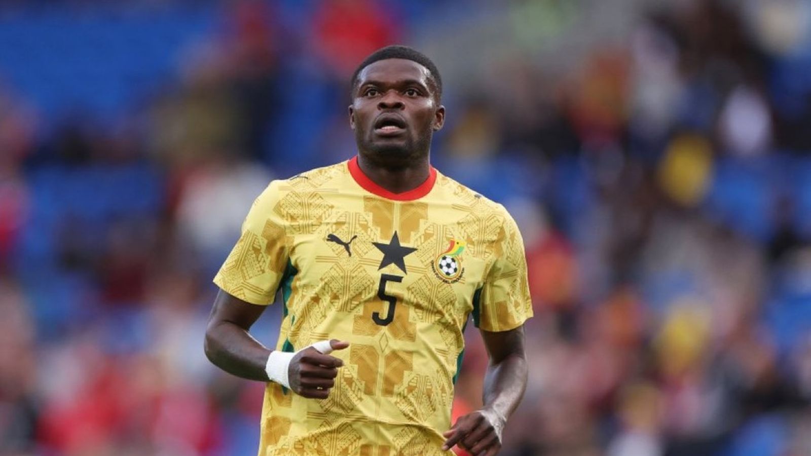 The Ghanaian player in the middle of a match wearing his yellow national team jersey