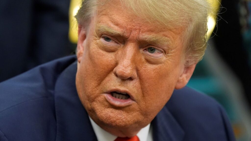 Donald Trump with an angry expression while speaking with several men wearing elegant suits.