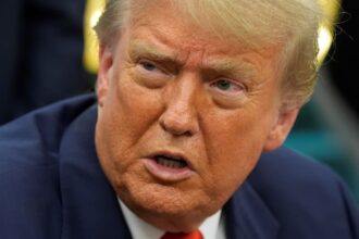 Donald Trump with an angry expression while speaking with several men wearing elegant suits.