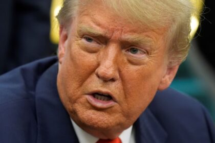 Donald Trump with an angry expression while speaking with several men wearing elegant suits.
