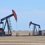 A panoramic view of two oil drilling rigs with a beautiful background