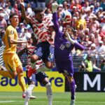 A United States player battling against the goalkeeper and a pair of Australian defenders while trying to score a goal