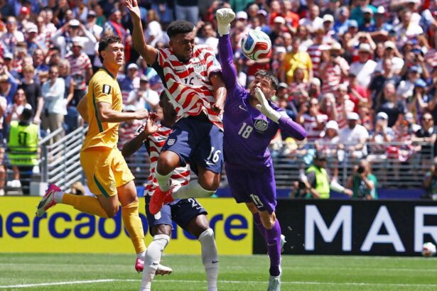 A United States player battling against the goalkeeper and a pair of Australian defenders while trying to score a goal