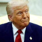 Donald Trump smiling sarcastically while looking to the side at one of his aides