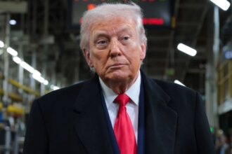 Donald Trump wearing an elegant suit while walking through a manufacturing facility